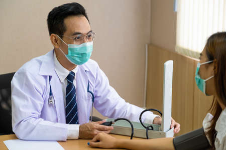 Doctor wearing surgical face mask while doing medical for patient inside of the hospital. Medical service check up.の写真素材
