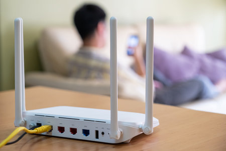 Selective focus at router. Internet router on working table with blurred man using tablet at the background. Fast and high speed internet connection from fiber line with LAN cable connection.の写真素材
