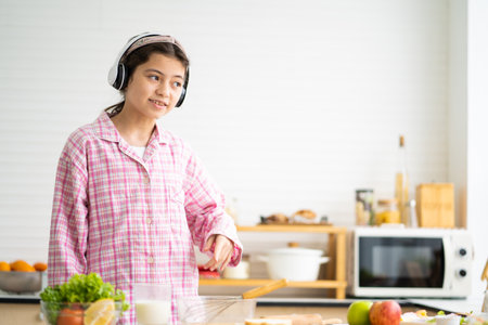 Young Caucasian girl wake up in the morning and eat fresh fruit for breakfast in the kitchen with different type of salad vegetable and healthy food. Good nutrition eating human body condition.の写真素材