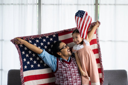 Father and daughter raise and holding American flag and celebrate United State independence date...
