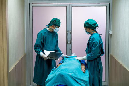 Selective focus at face of the doctor while moving out the body of pass away patient while doctor covering face inside of the surgery operation room in the hospital. Illness and death concept.の写真素材