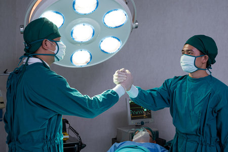 Portrait shot of doctor and assistance nurse wearing surgical coat while doing surgical operation for patient inside of the hospital. Medical and professional service occupation.の写真素材