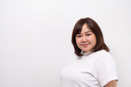 Young beautiful Asian oversize women smile with positive emotion, feeling happy and proud with her body size. Portrait shot on white background with copy space.の写真素材