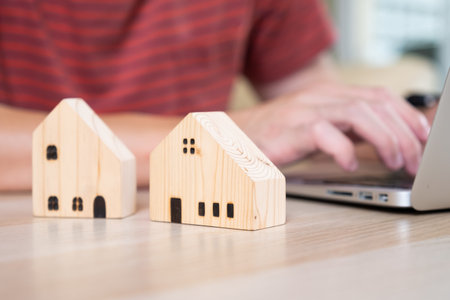 Selective focus at wooden house model with calculator and paper note on wood table. Saving plan and interest rate to buy property, house. Personal financial concept for own a house.の写真素材