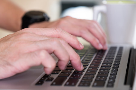 Men hand typing on computer keyboard while working from home or using internet for online shopping and social network. Laptop device and Wireless technology concept.の写真素材