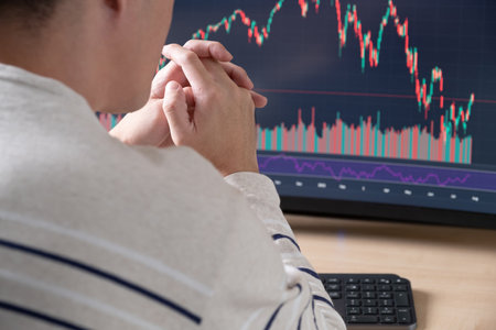 Selective focus at human hand while typing on laptop computer keyboard to execute buy or sell order while trade for stock exchange or crypto currency exchange with blurred indicator screen.の写真素材