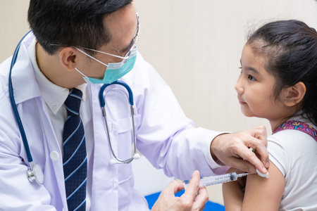 Young Asian girl get medical vaccination from the doctor with her mother sit and hold to support. Medical service for young people, kids. Immunity dose injection to prevent illness in children.の写真素材