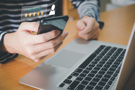 Selective focus at human hand while typing on laptop or smartphone to feedback on excellent customer service with five star score with smile. Service evaluation concept with futuristic icon.の写真素材