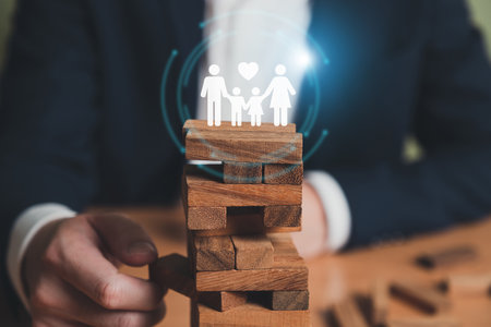 Insurance agent with formal suit using hand to protect customer family from falling wood brick. With icon of the family with shield to prevent the risk and accident. Risk management with insurance.の写真素材