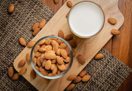 Almond milk in the glass with almond in the glass bowl on the wooden table.の写真素材