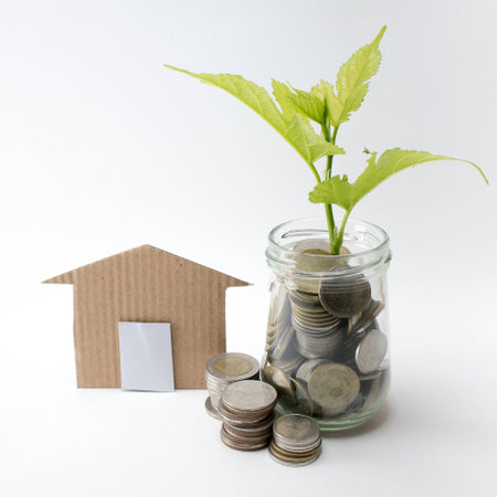 Money in glass bottle and plant growing on the coins, saving money for home concept.の写真素材