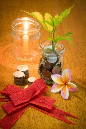Saving money concept, coins in glass and red bottle on wooden table.の写真素材