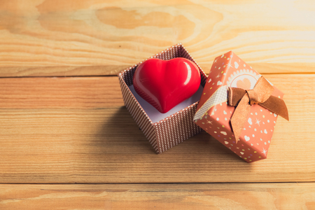 Gift of love. hearty gift. A gift box with a red heart inside. On the wooden floorの写真素材