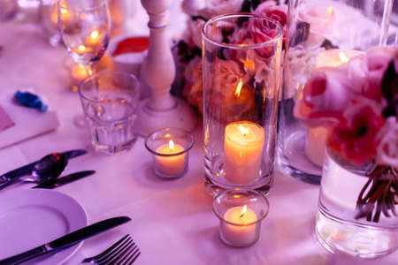 Close up view of a beautiful table arrangment of lighted candles, flowers and colorful mood lighting...