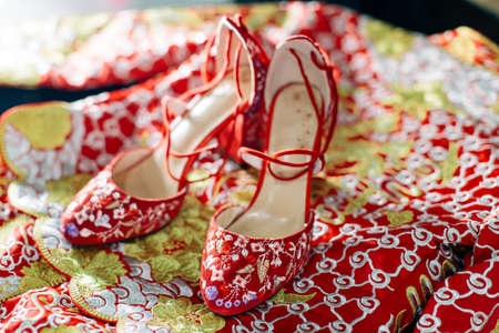 Close up of a pair of red color chinese wedding shoes with intricate oriental patternsの写真素材