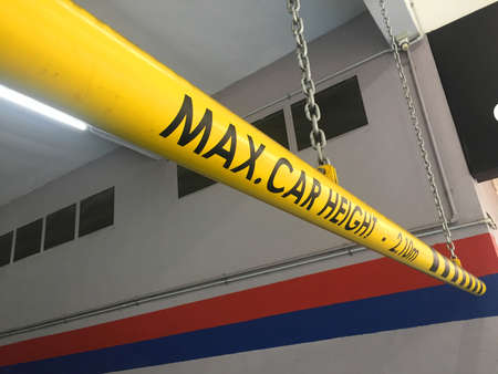 View of an bright yellow height restriction bar at the entrance of a basement parking lot. It is to...