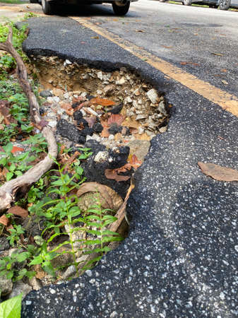 Close up of a big pothole at the edge of the roadの写真素材