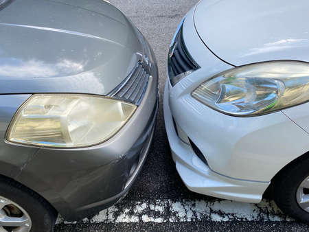 Close up view of two cars parking bumper to bumper very near each other head on