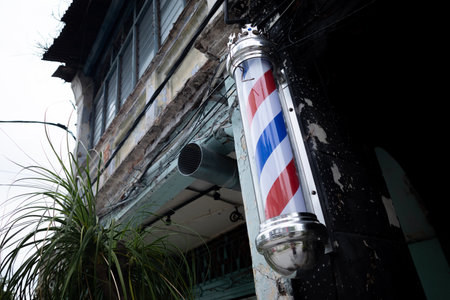 A color barber pole with red, blue and white stripes attached outside a shopの写真素材