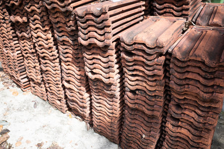 Stacks of unused old ceramic roof tiles lying on the ground of a construction siteの写真素材