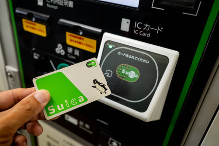 Nagano, Japan - 2 November 2023 : Close up of a hand holding a SUICA electronic money card in front of a sensor to make payment for a purchase at Nagano, Japan.のeditorial素材