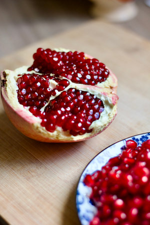 half of a fresh red pomegranate on a wooden tableの写真素材