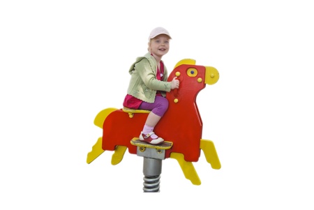 smiling happy child girl on a wooden horse isolated over white, copyspaceの写真素材