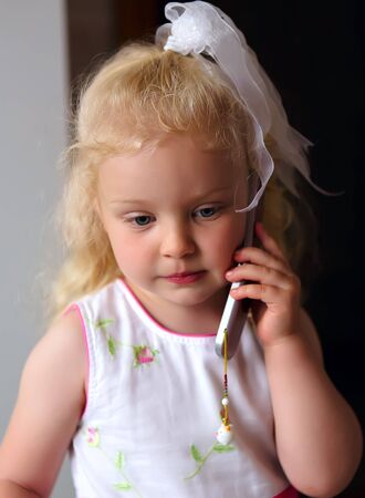 little beautiful caucasian girl listening to mobile phoneの写真素材