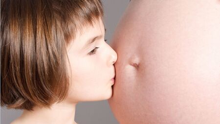 little girl kiss the belly's motherの写真素材