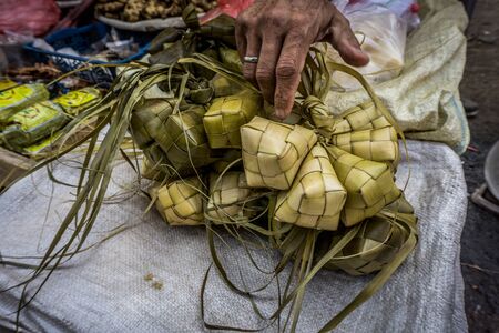 A hand touch rice wraped with coconut leaf with diamond shape in traditional market Bogor Indonesia