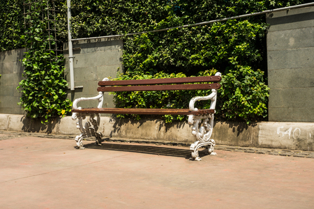 bench on the sidewalk with bush green tree as backgroundの写真素材