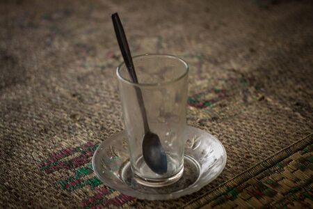 an empty glass on top of traditional mat with spoon javaの写真素材