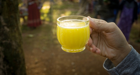 hand holding a glass of yellow corn milk in indonesia