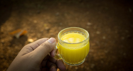 hand holding a glass of yellow corn milk in indonesia