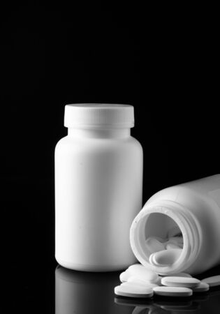 bottle with white pills on black background の写真素材
