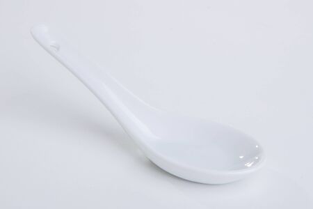 White empty ceramic spoon for soup on white backgroundの写真素材