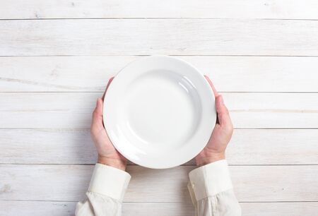 Business lunch and healthy food theme: man's hand holding a white empty plateの写真素材