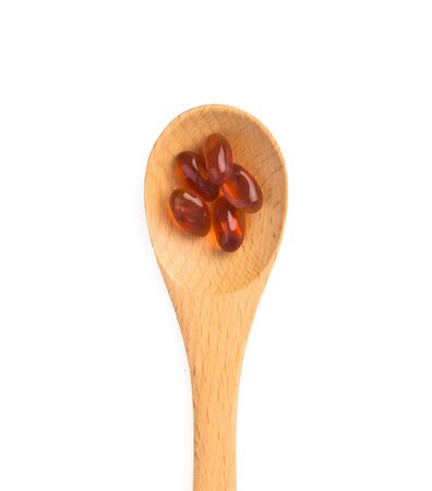 Pills in wooden spoon isolated on whiteの写真素材