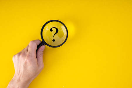 Magnifying glass with QUESTION MARK in focus on yellow background. concept of search and research.の写真素材