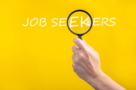 Job seekers. Hand holding magnifying glass focusing on the wordsの写真素材