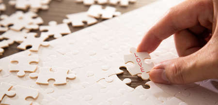 Hand completing the a last piece of jigsaw puzzle with love word. Family love conceptualの写真素材