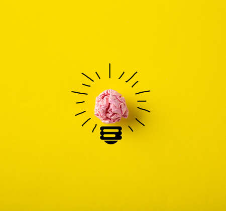 Inspiration concept crumpled paper light bulb metaphor for good idea on yellow backgroundの写真素材