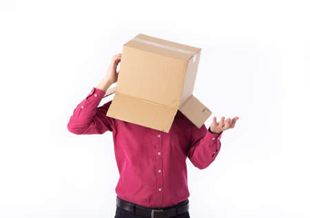 man in a red shirt with a cardboard box on his head makes a gesture with his hands isolated on white...