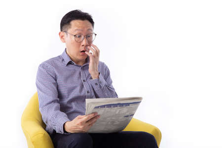 Surprised man reading the news seated on a bench isolated on white backgroundの写真素材