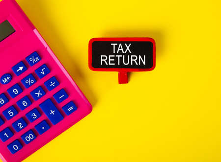 Top view of calculator and a tag with TAX RETURN word on yellow backgroundの写真素材