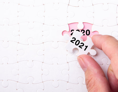 Hand putting a piece of 2021 white jigsaw puzzle and close up a year 2020. End Of Year 2020