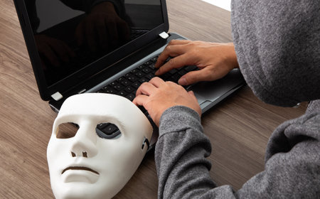Thief hacker in mask stealing personal information from laptop. Concept hacking.の写真素材