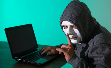 Thief hacker in mask stealing personal information from laptop. Concept hacking.の写真素材