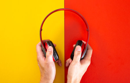 hand holding a headphones on red and yellow background. Music concept.の写真素材