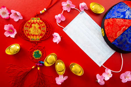 Face mask and Chinese ancient ingot and flowers on red color. Chinese new year background and health...